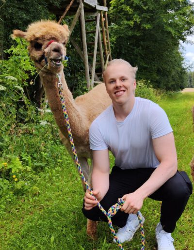 Mann mit Alpaka in der Natur.
