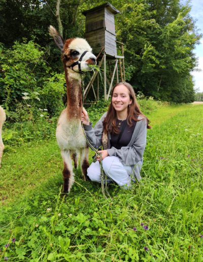 Frau mit Alpaka in der Natur.