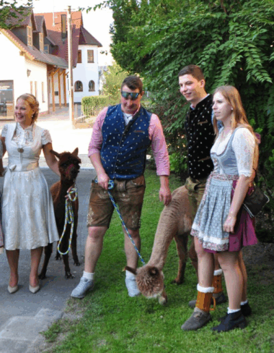 Braut steht mit Gästen und einem Alpaka